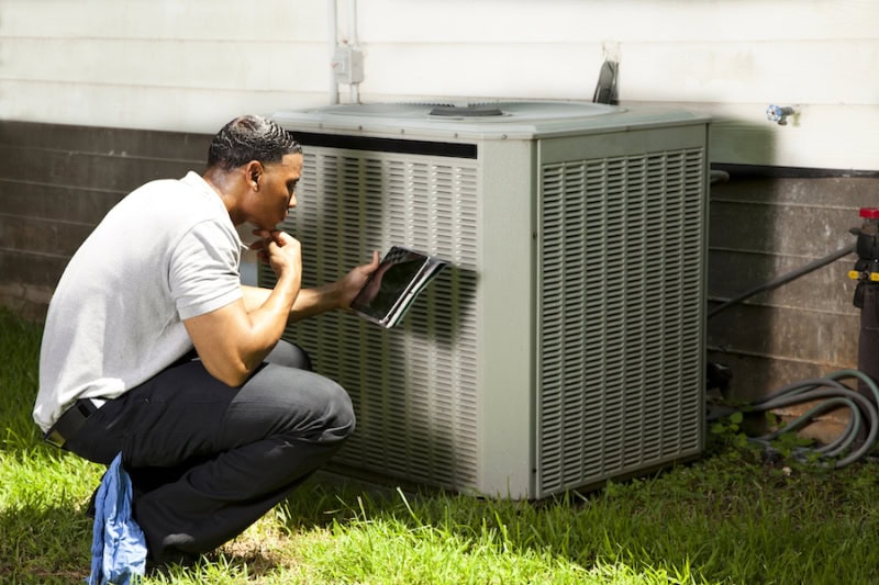 HVAC technician reviewing diagnostics on laptop to see if homeowner in Fort Worth needs a new air conditioning unit.