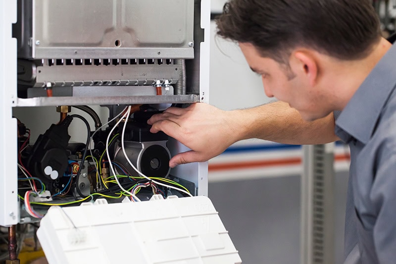 Hawk Plumbing Heating & Air Conditioning technician diagnosing problems with homeowner's heat pump.